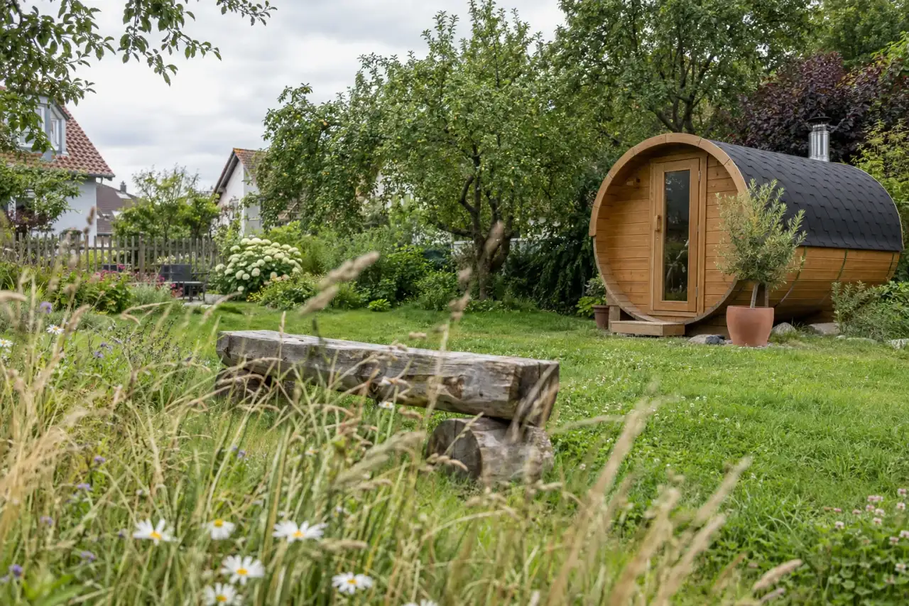 Kompakte Sauna zwischen Gräsern mit offenem Rasen und Holzsitz.