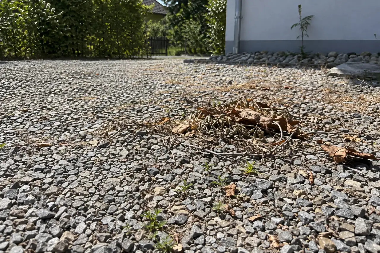 Kahle sonnenbeschienene Schotterfläche mit wenig Schutz und eingetragenem Schmutz