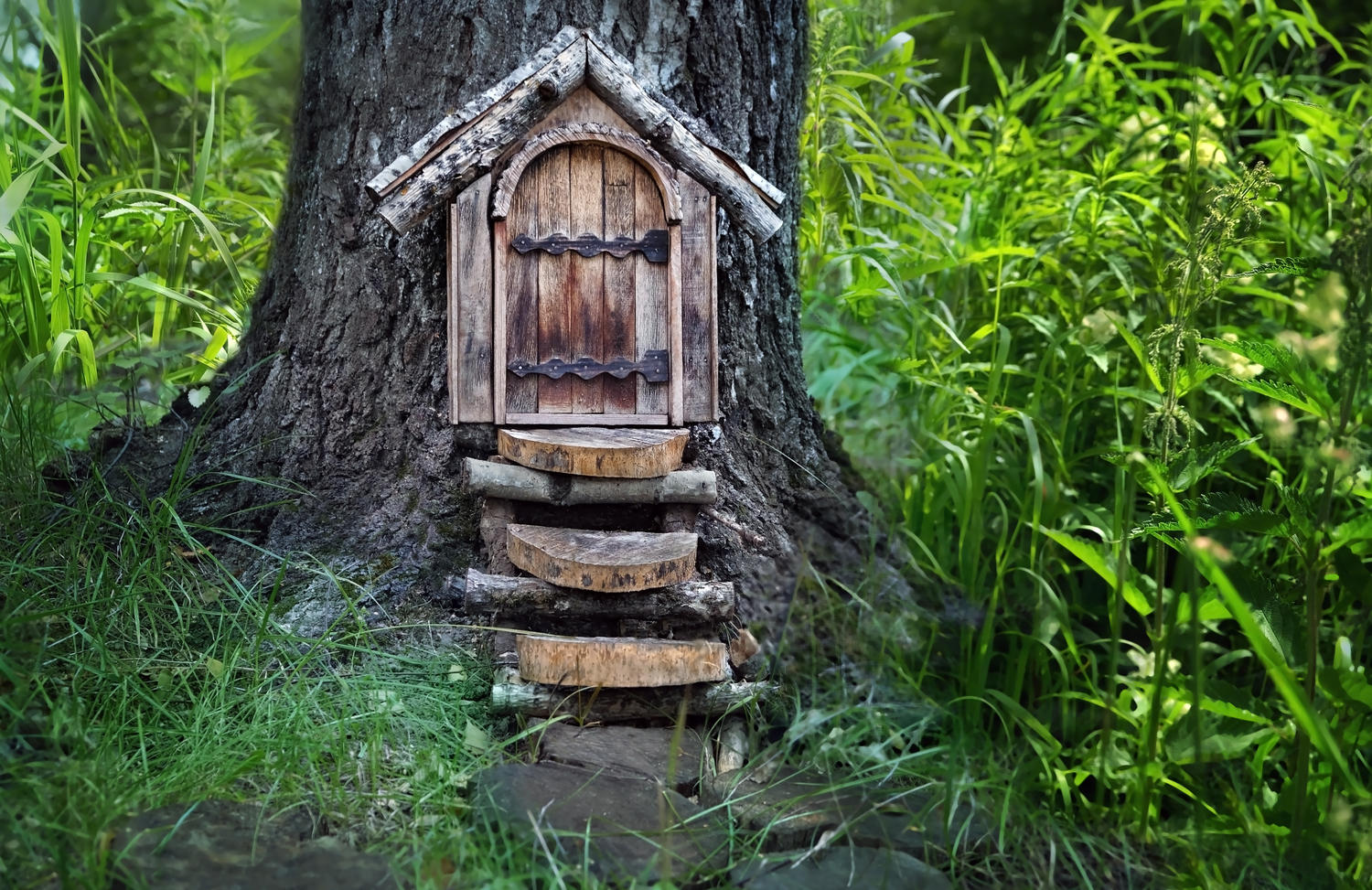 Feenhaus mit Tür aus Holzresten an einem Baumstamm
